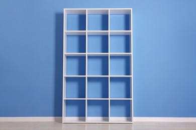 Photo of Empty shelving unit near blue wall indoors