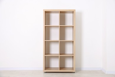 Photo of Empty wooden shelving unit near white wall indoors