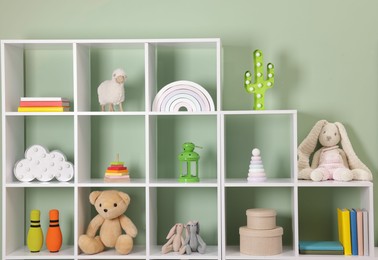 Photo of Shelving unit with toys near olive wall indoors