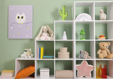 Photo of Shelving unit with toys near olive wall indoors