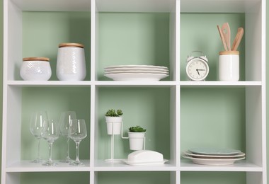 Photo of Shelving unit with dishware near olive wall indoors