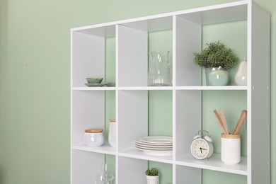 Photo of Shelving unit with dishware near olive wall indoors