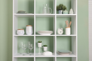 Photo of Shelving unit with dishware near olive wall indoors