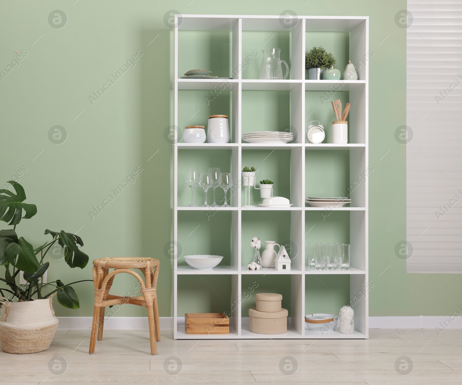 Photo of Shelving unit with dishware near olive wall indoors