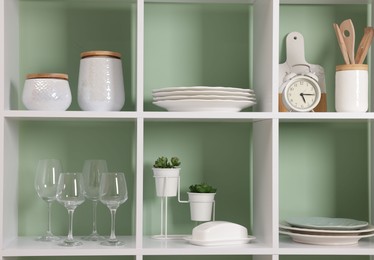 Photo of Shelving unit with dishware near olive wall indoors