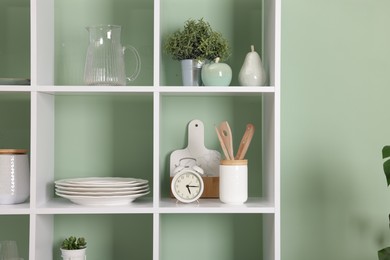 Photo of Shelving unit with dishware near olive wall indoors