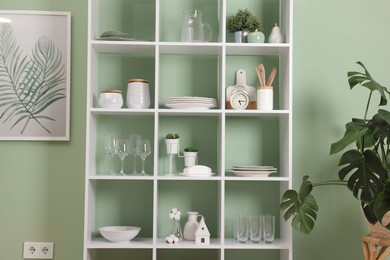 Photo of Shelving unit with dishware near olive wall indoors