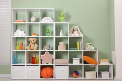 Photo of Shelving unit with toys near olive wall indoors