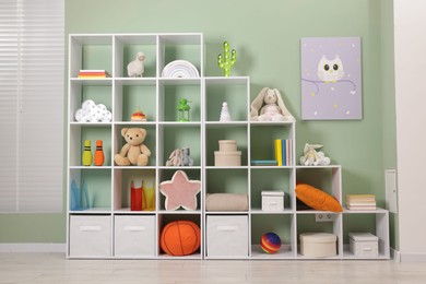 Photo of Shelving unit with toys near olive wall indoors