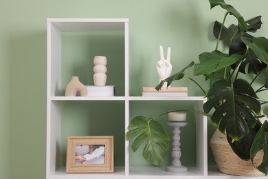 Photo of Shelving unit with decor near olive wall indoors