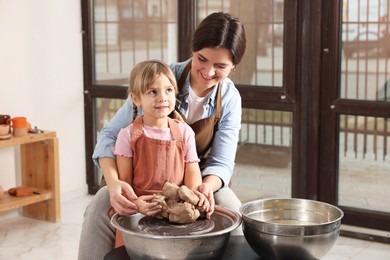 Photo of Hobby and craft. Smiling mother with her daughter making pottery indoors