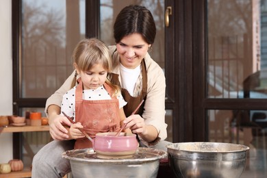 Photo of Hobby and craft. Smiling mother with her daughter making pottery indoors