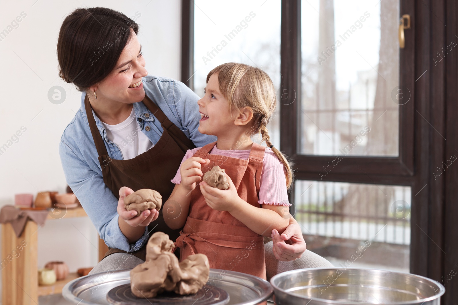 Photo of Hobby and craft. Smiling mother with her daughter making pottery indoors