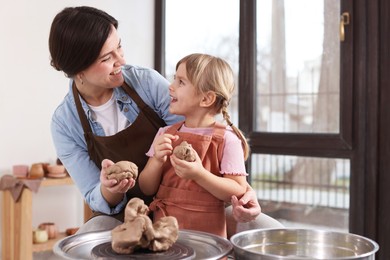 Photo of Hobby and craft. Smiling mother with her daughter making pottery indoors