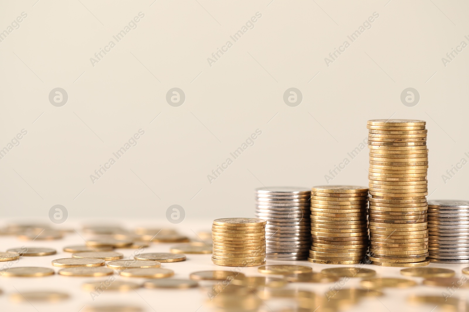 Stacks of coins on white table against light background, closeup. Space for text Photo of Stacks of coins on white table against light background, closeup. Space for text