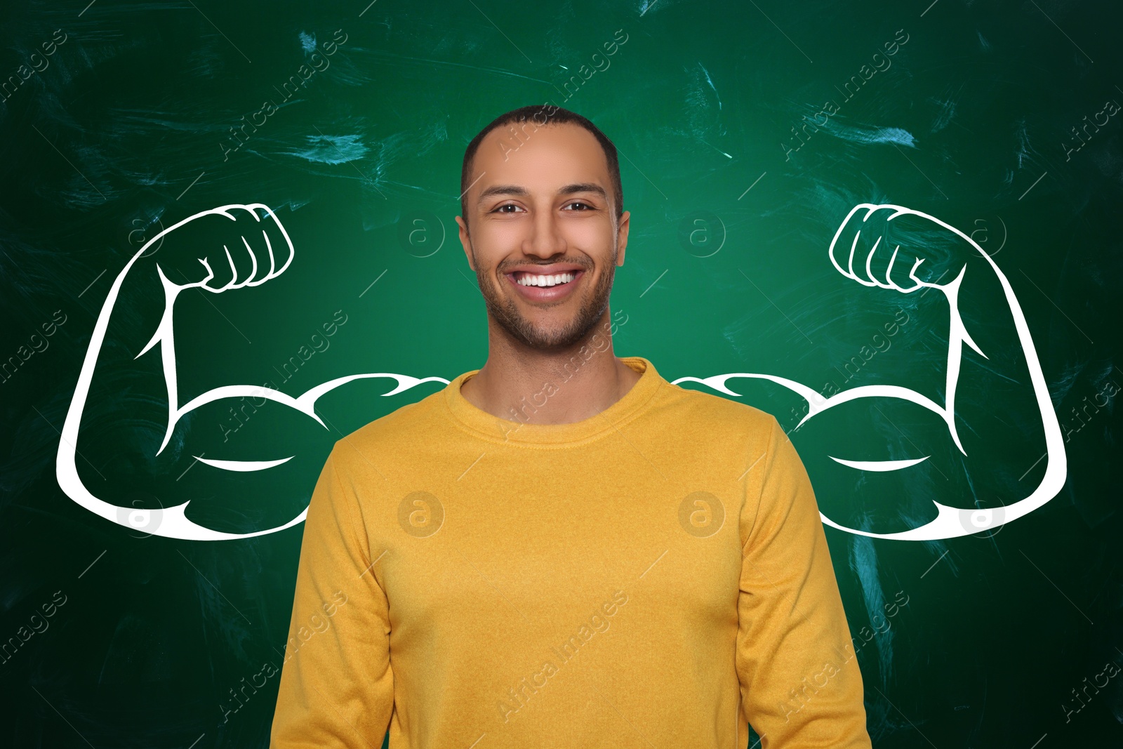 Image of Happy man with drawing of strong arms behind him on green chalkboard