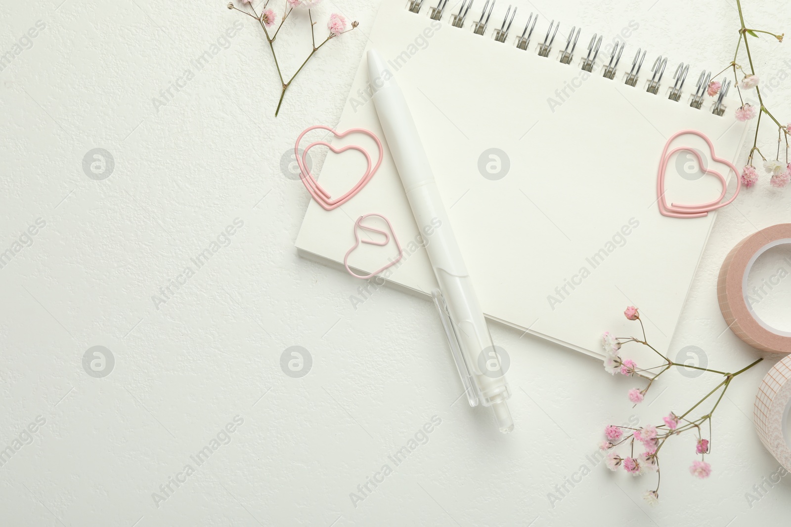 Photo of Paper clips, other stationery and flowers on white background, flat lay. Space for text