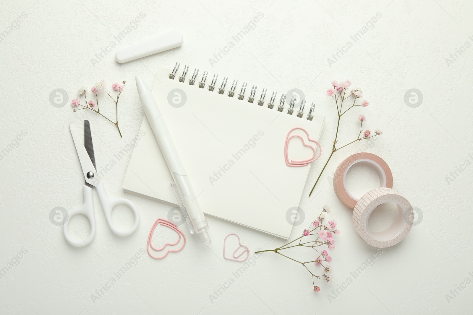 Photo of Paper clips, other stationery and flowers on white background, flat lay