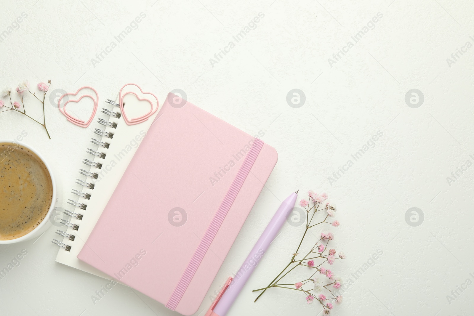 Photo of Paper clips, other stationery, coffee and flowers on white background, flat lay. Space for text