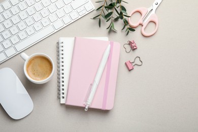 Binder clips, other stationery, coffee, computer keyboard, mouse and green branches light grey background, flat lay. Space for text