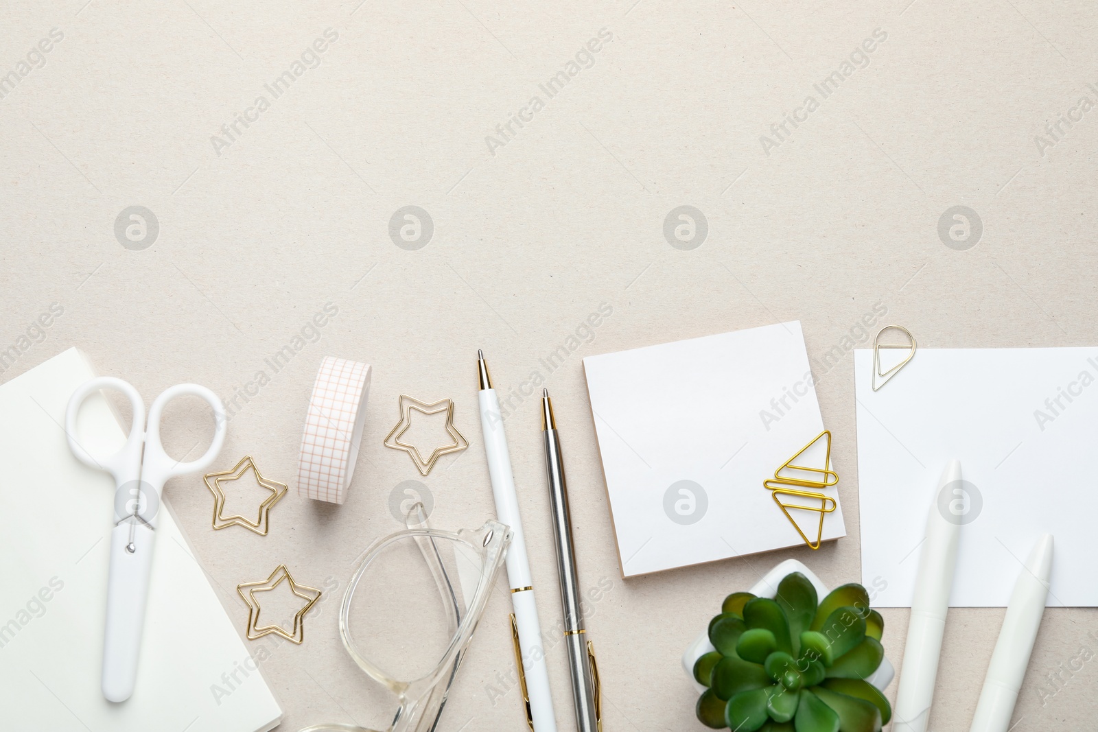 Photo of Paper clips, other stationery, glasses and decor on light grey background, flat lay. Space for text