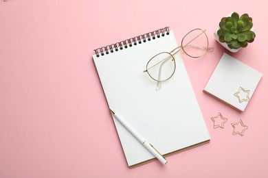 Paper clips, other stationery, glasses and decor on pink background, flat lay. Space for text