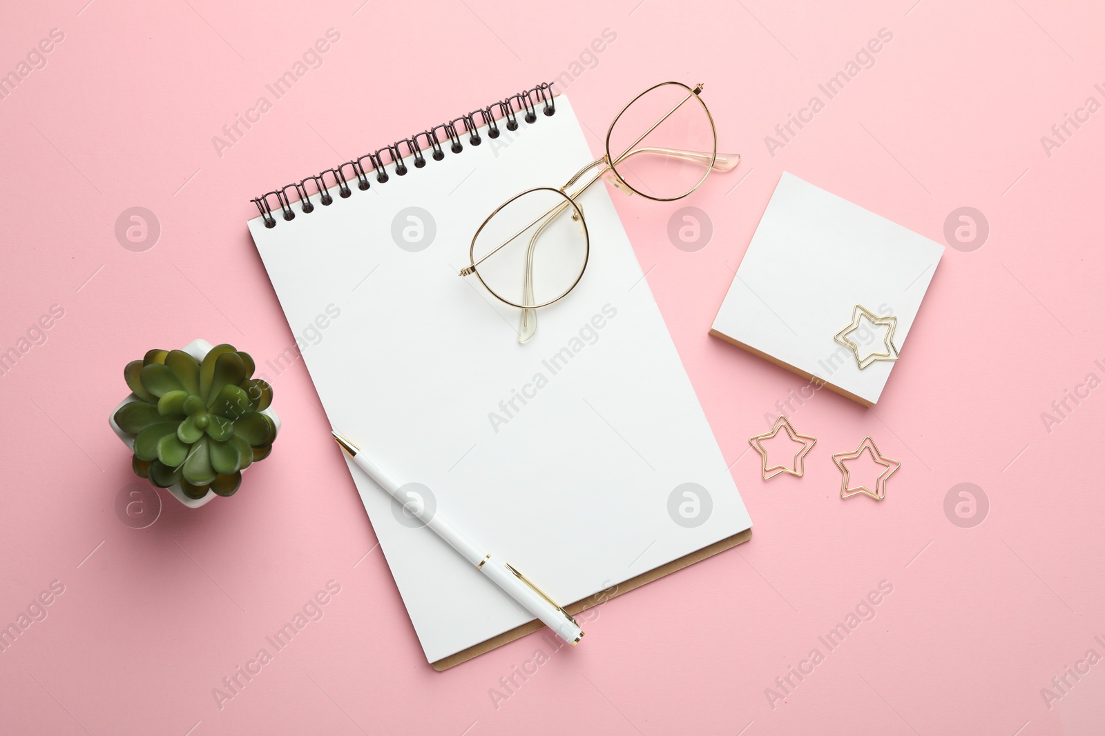 Photo of Paper clips, other stationery, glasses and decor on pink background, flat lay