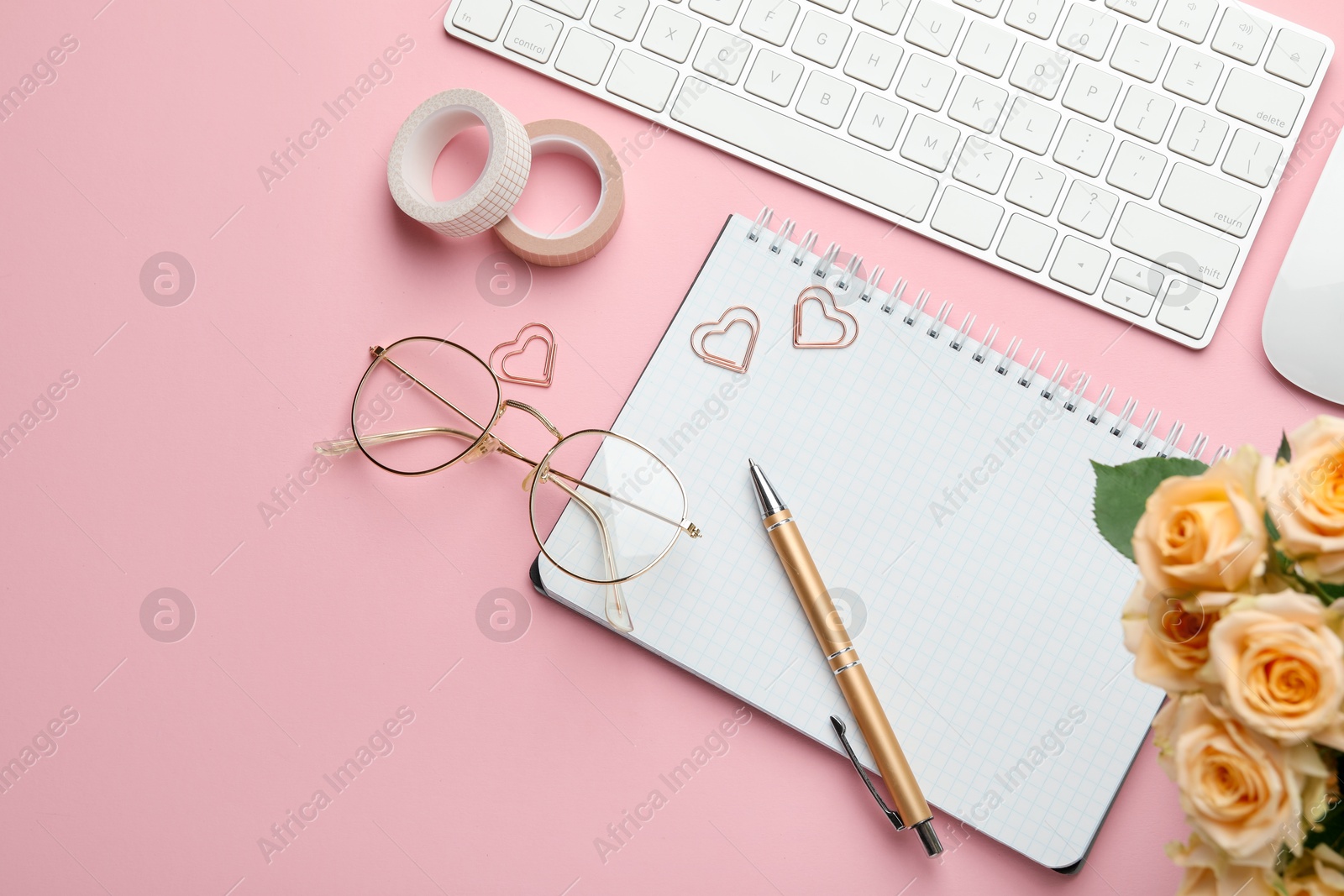 Photo of Paper clips, other stationery, computer keyboard, glasses and roses on pink background, flat lay. Space for text