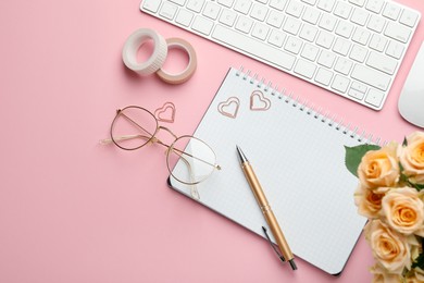 Paper clips, other stationery, computer keyboard, glasses and roses on pink background, flat lay. Space for text