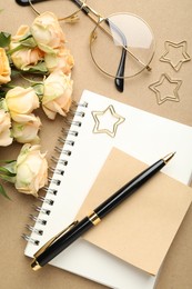 Photo of Paper clips, other stationery, glasses and roses on beige background, flat lay