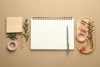 Photo of Binder clips, other stationery and green twigs on beige background, flat lay