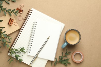 Binder clips, other stationery, coffee and green branches on beige background, flat lay