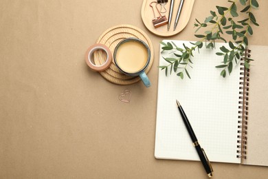 Binder clips, other stationery, coffee and green branches on beige background, flat lay. Space for text