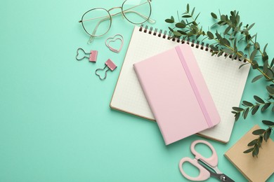 Photo of Binder clips, other stationery, glasses and green branches on turquoise background, flat lay. Space for text