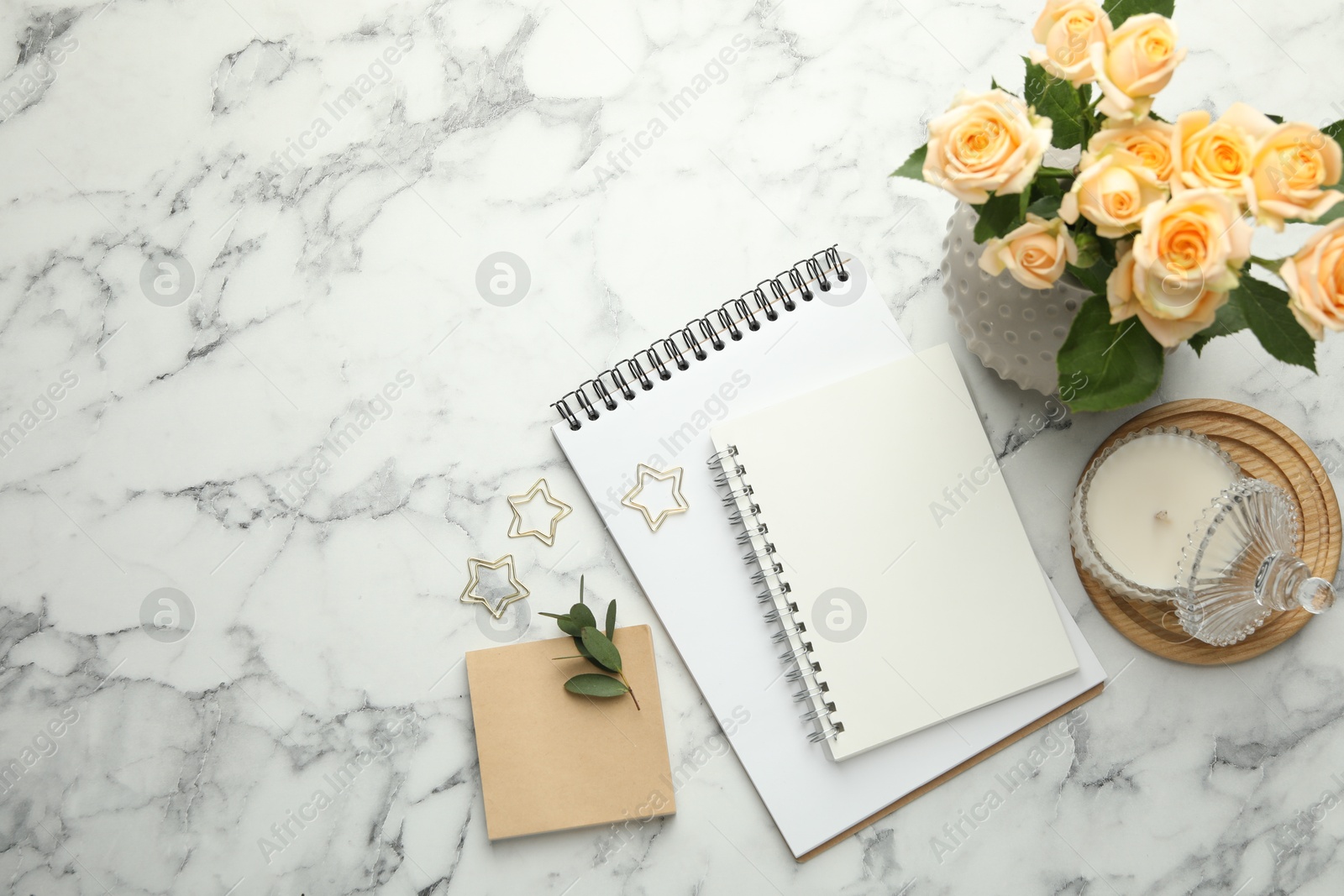 Photo of Paper clips, notebooks and decor on white marble table, flat lay. Space for text