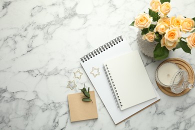 Paper clips, notebooks and decor on white marble table, flat lay. Space for text