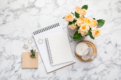 Paper clips, notebooks and decor on white marble table, flat lay