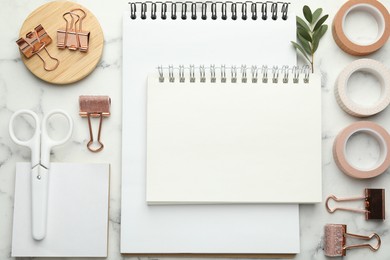 Binder clips, other stationery and green twig on white marble table, flat lay