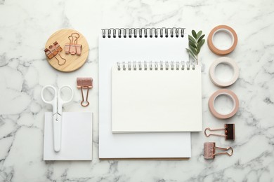 Photo of Binder clips, other stationery and green twig on white marble table, flat lay