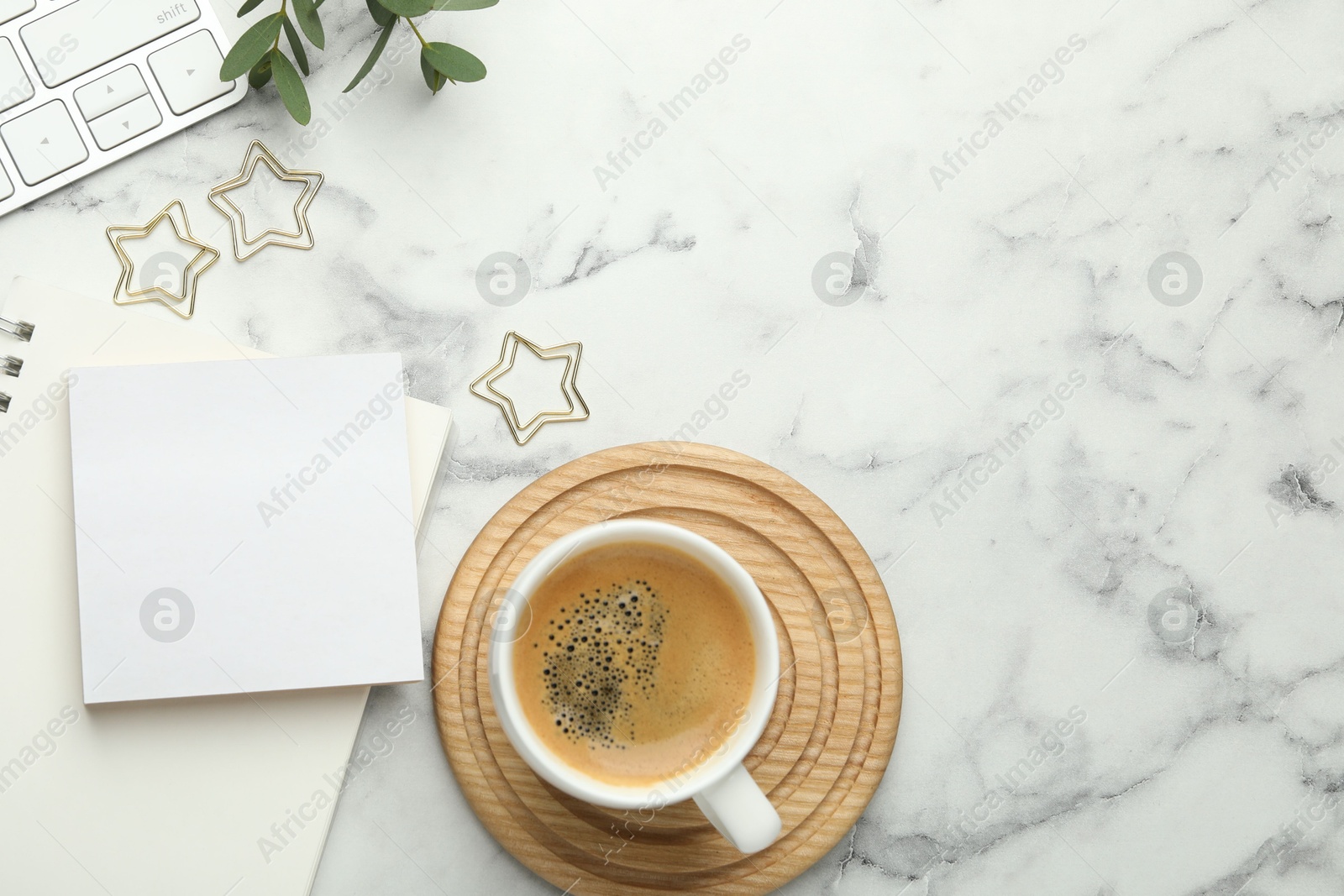 Photo of Paper clips, other stationery, coffee and green leaves on white marble table, flat lay. Space for text