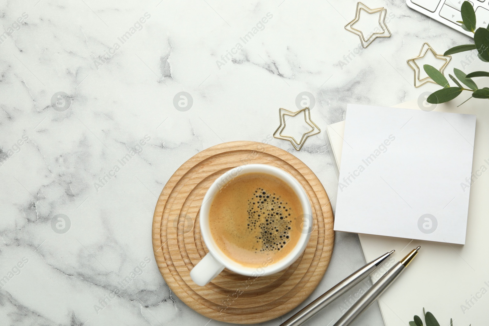 Photo of Paper clips, other stationery, coffee and green leaves on white marble table, flat lay. Space for text