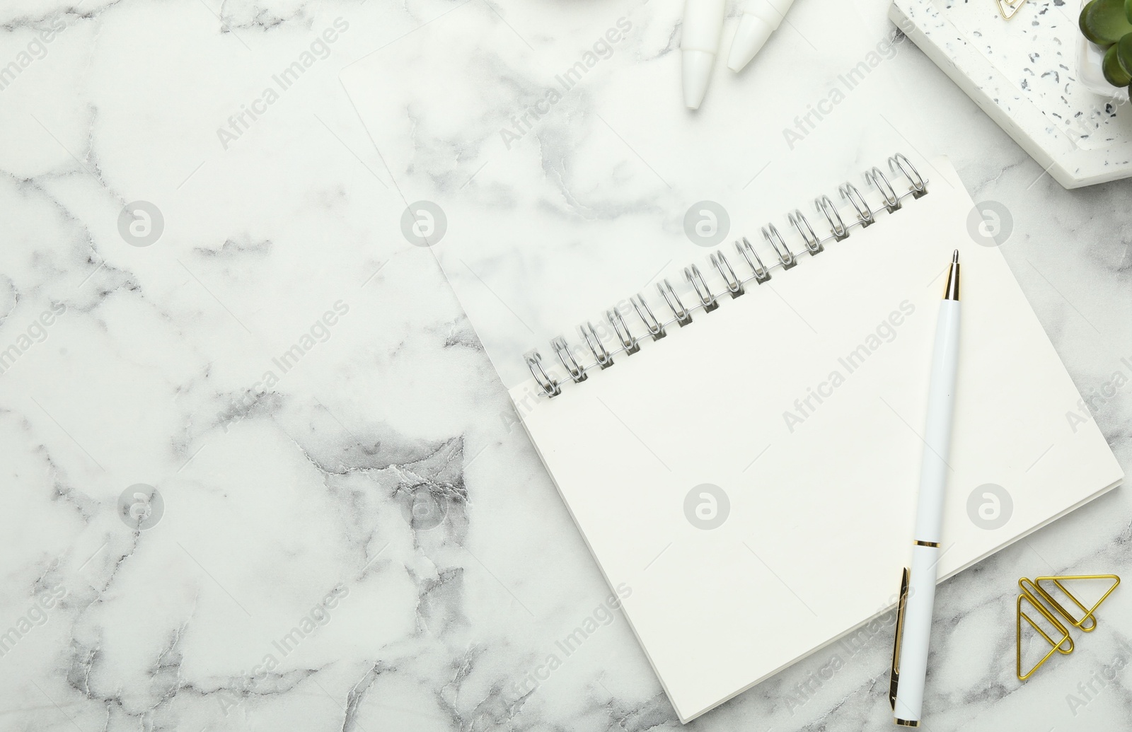 Photo of Paper clips, notebook and pen on white marble table, flat lay. Space for text