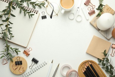 Frame of paper clips, other stationery, coffee and green branches on white background, flat lay. Space for text