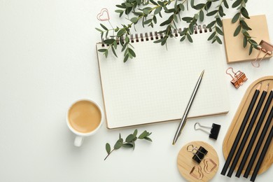 Paper clips, other stationery, coffee and green branches on white background, flat lay. Space for text