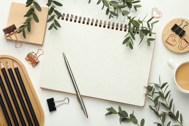 Paper clips, other stationery, coffee and green branches on white background, flat lay