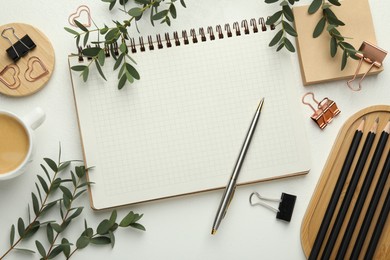 Paper clips, other stationery, coffee and green branches on white background, flat lay