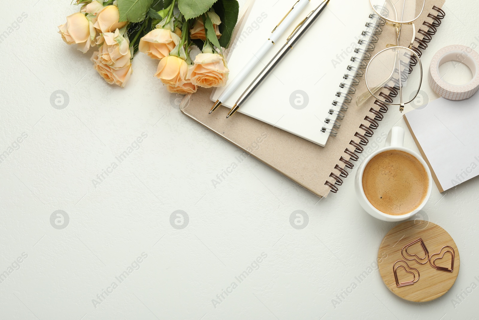 Photo of Paper clips, other stationery, coffee, glasses and roses on white background, flat lay. Space for text