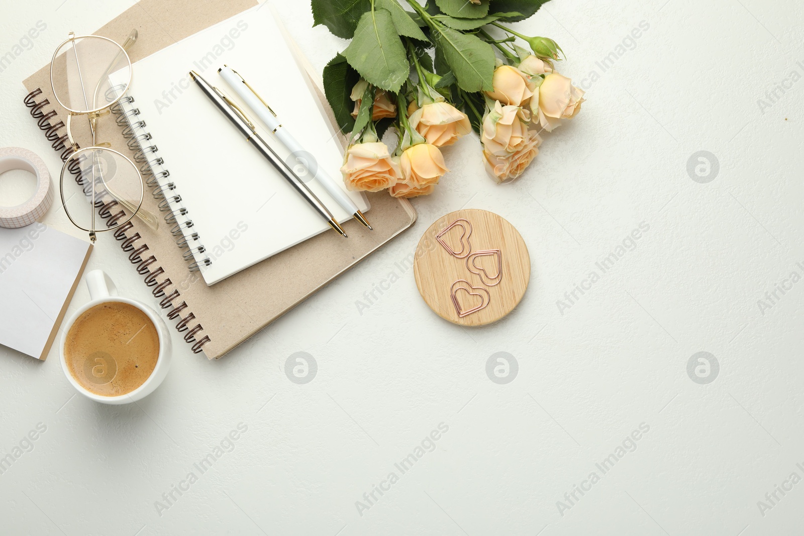 Photo of Paper clips, other stationery, coffee, glasses and roses on white background, flat lay. Space for text