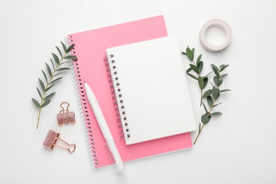 Binder clips, other stationery and green branches on white background, flat lay