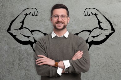 Confident man with drawing of strong arms behind him on grey background